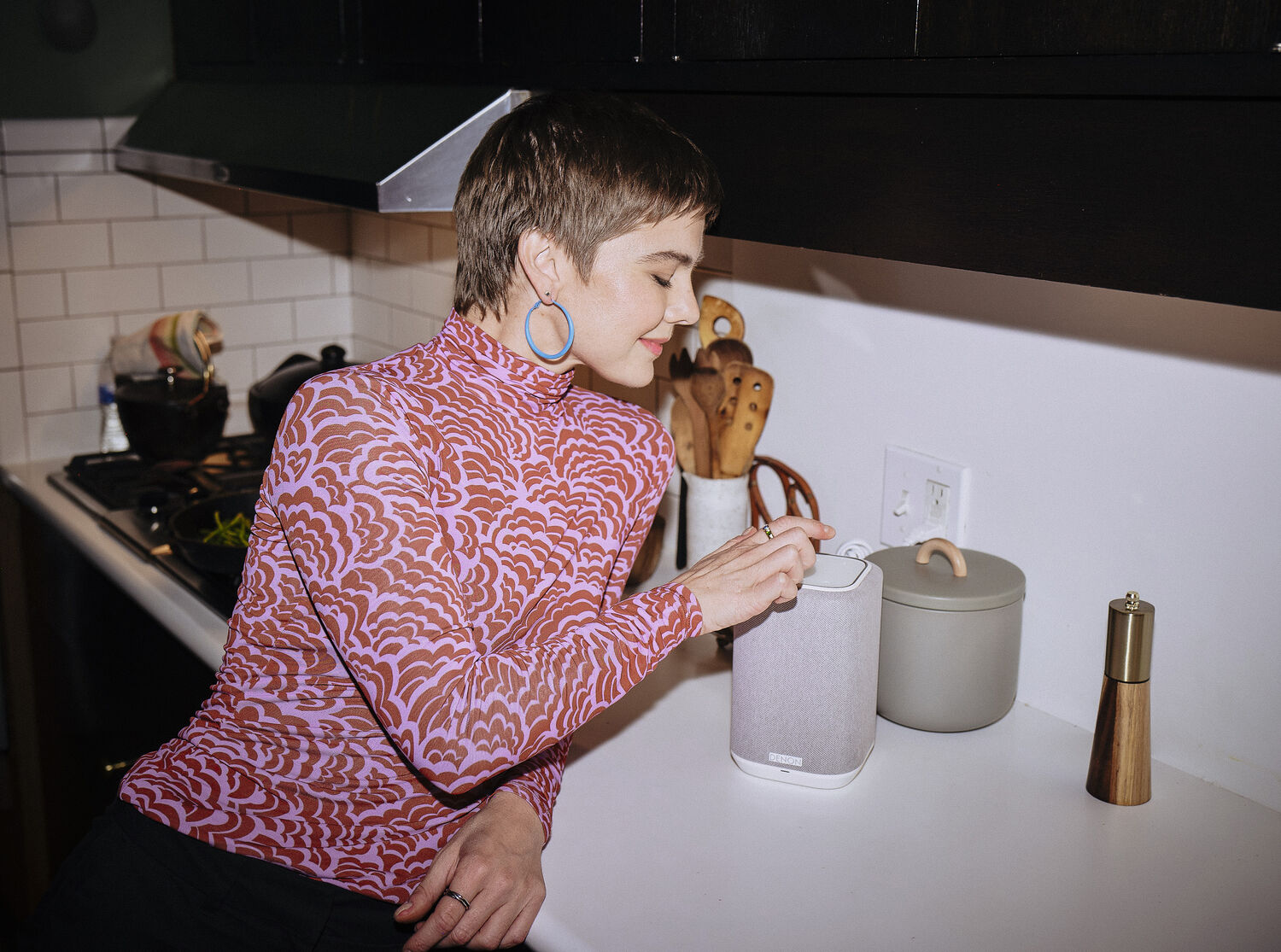 A woman touching buttons on a Denon speaker
